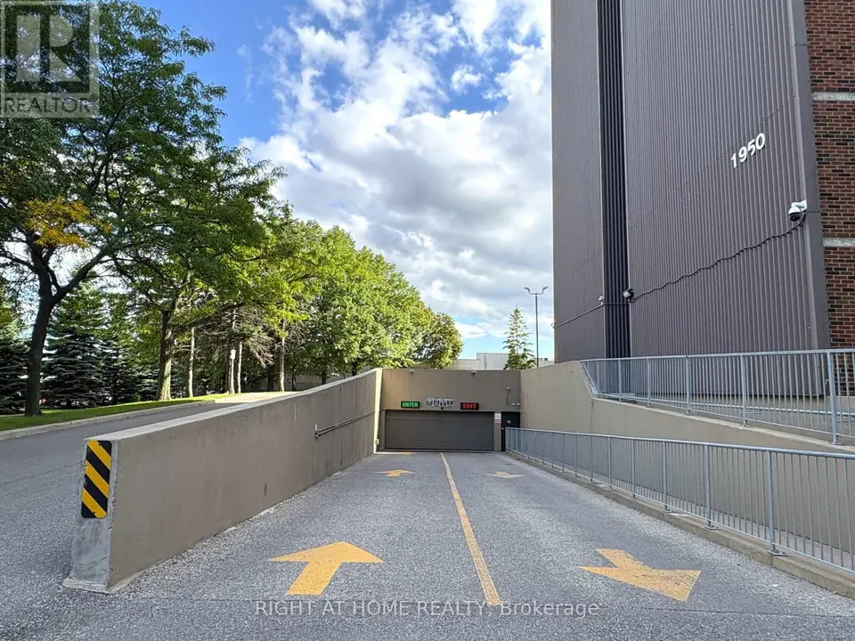 Driveway ramp descending to an underground parking garage door marked Enter and Exit, beside the building marked 1950.